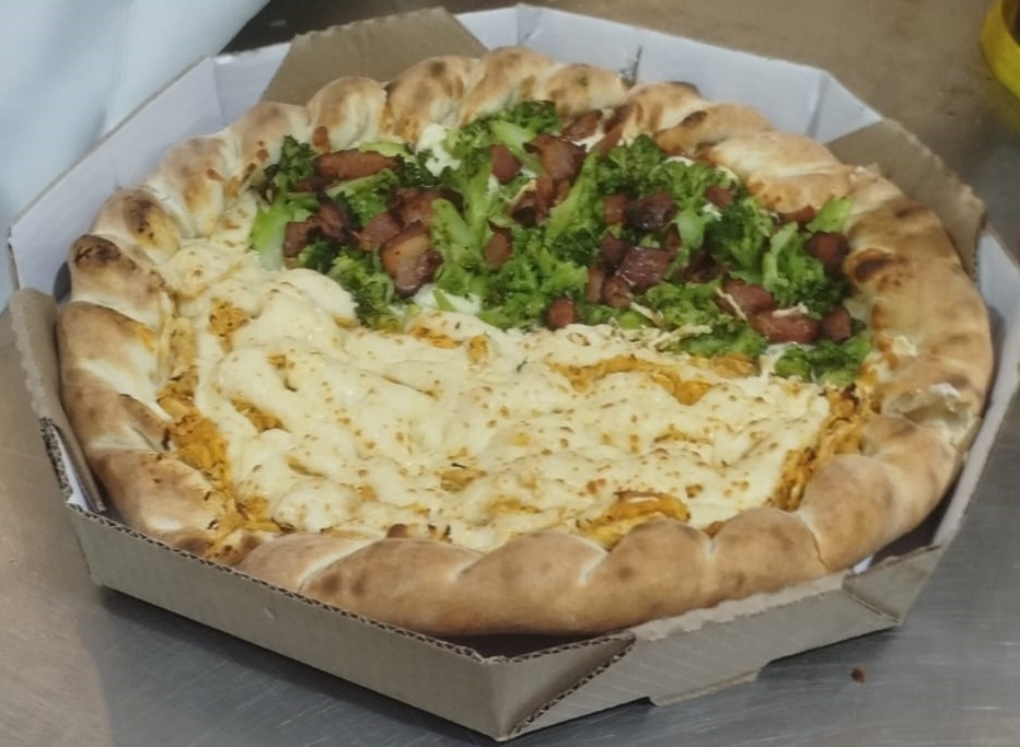 Pizzaiolo fatiando uma pizza recém-assada na Don Mussarelo, Parque Industrial, SJC